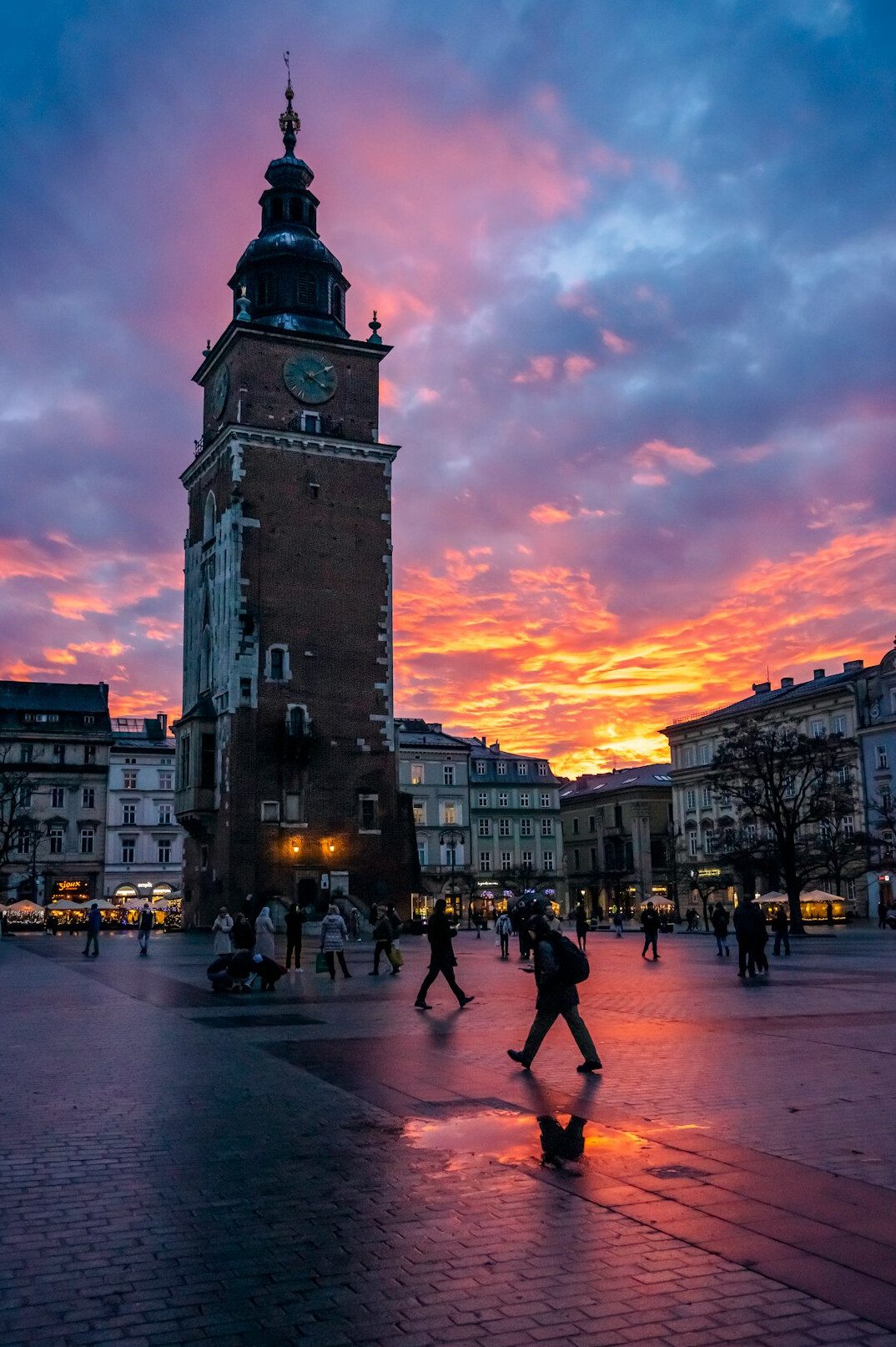 Silhouettes of people crossing a city plaza at sunset